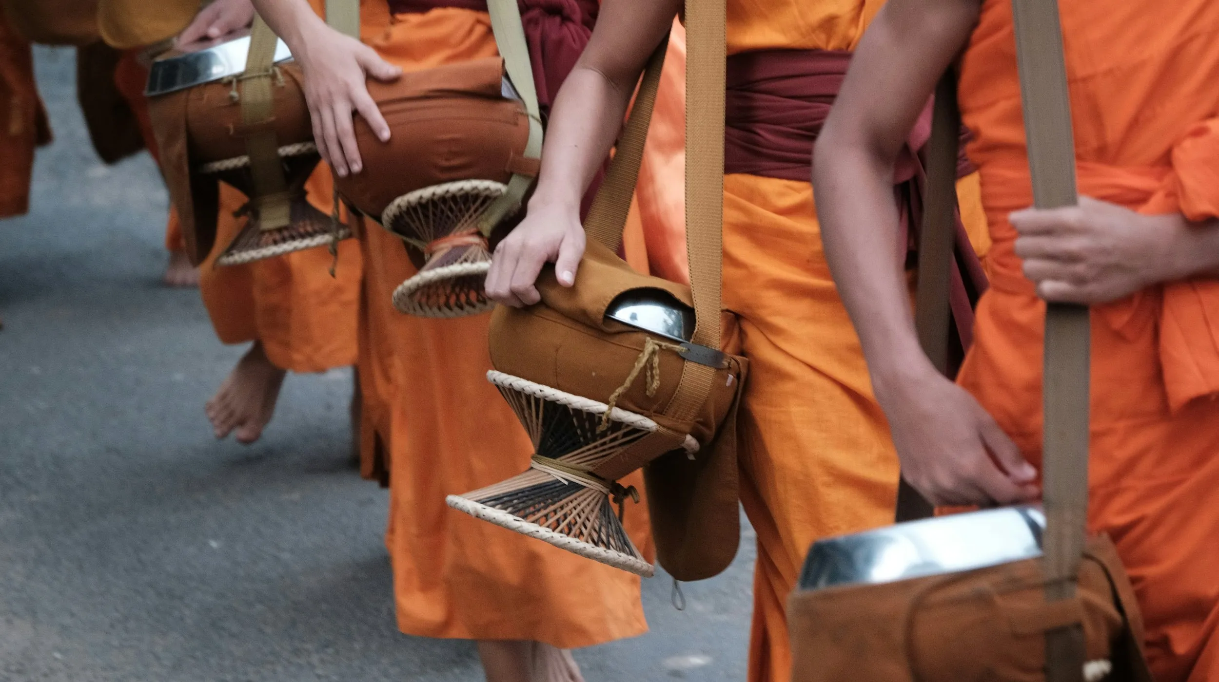 Des moines en robes orange défilent, portant des bols rituels, dans une scène culturelle vibrante.