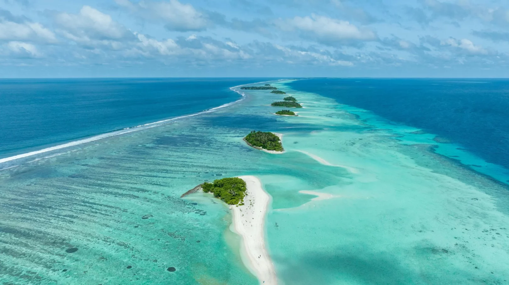 Une bande de sable immaculé au milieu d'une mer turquoise, offrant un paysage paradisiaque et apaisant.