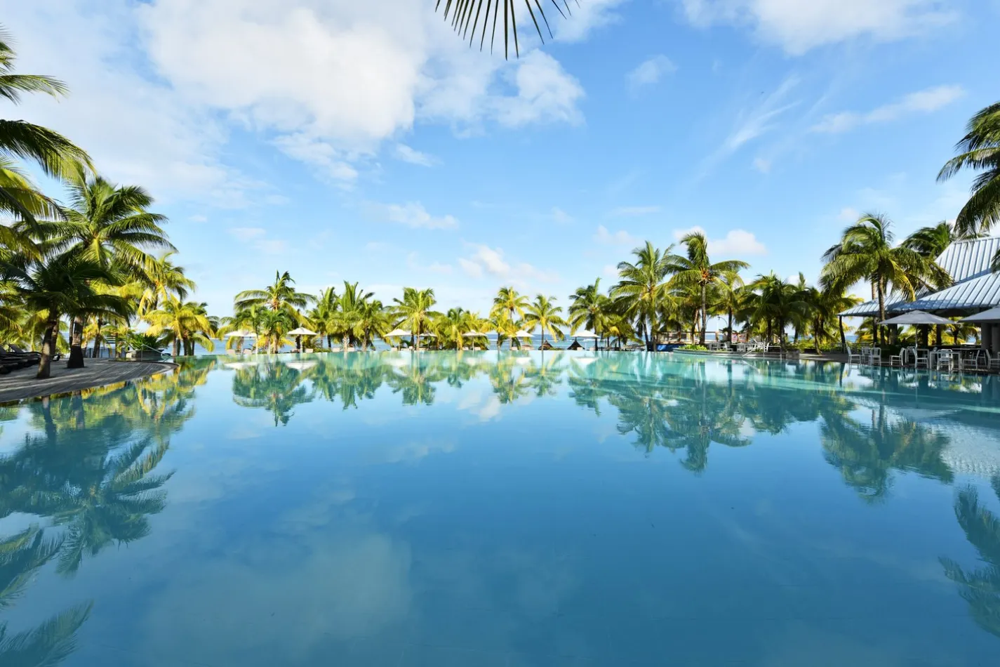 Hôtel Victoria de Beachcomber - Piscine à débordement entourée de palmiers, Île Maurice — ambiance tropicale et paisible.