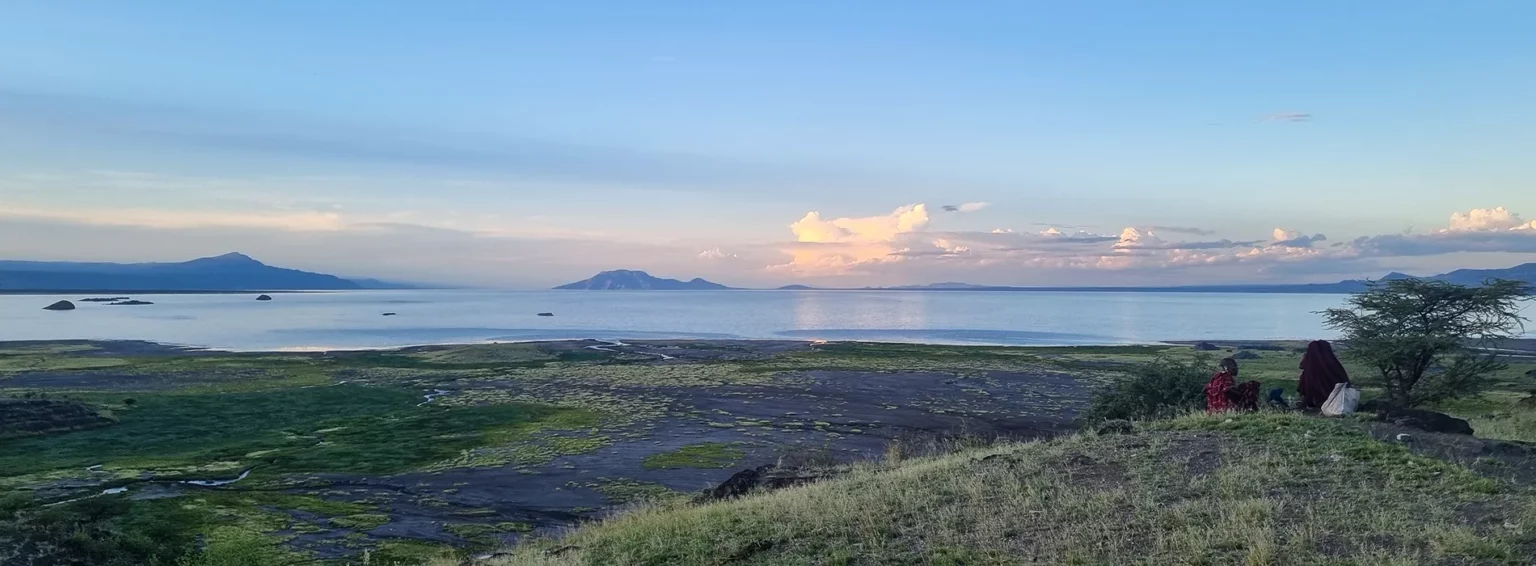 Un paysage serein au bord de l'eau, avec des collines verdoyantes sous un ciel lumineux.