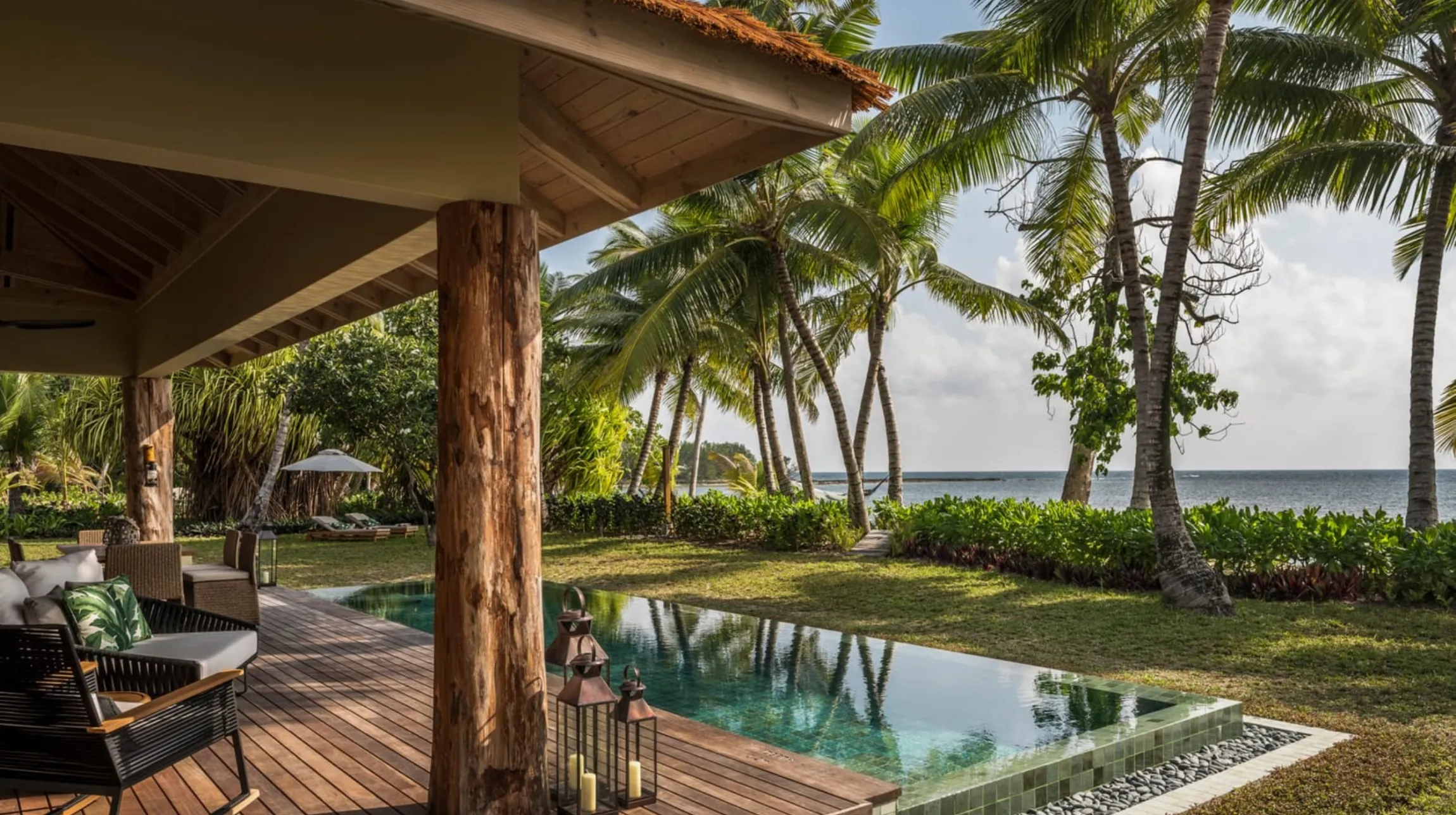 Un cadre tropical et paisible avec une piscine, des palmiers et une vue sur l'océan.