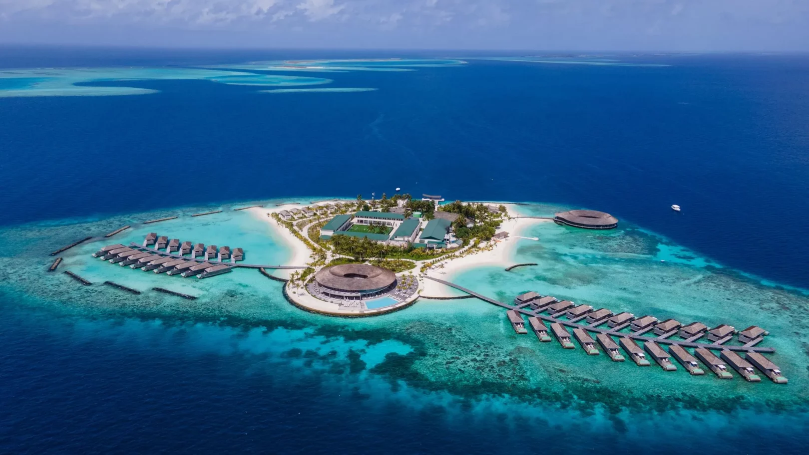 Île paradisiaque aux Maldives — eaux turquoise et villas sur pilotis entourées de plages de sable fin.