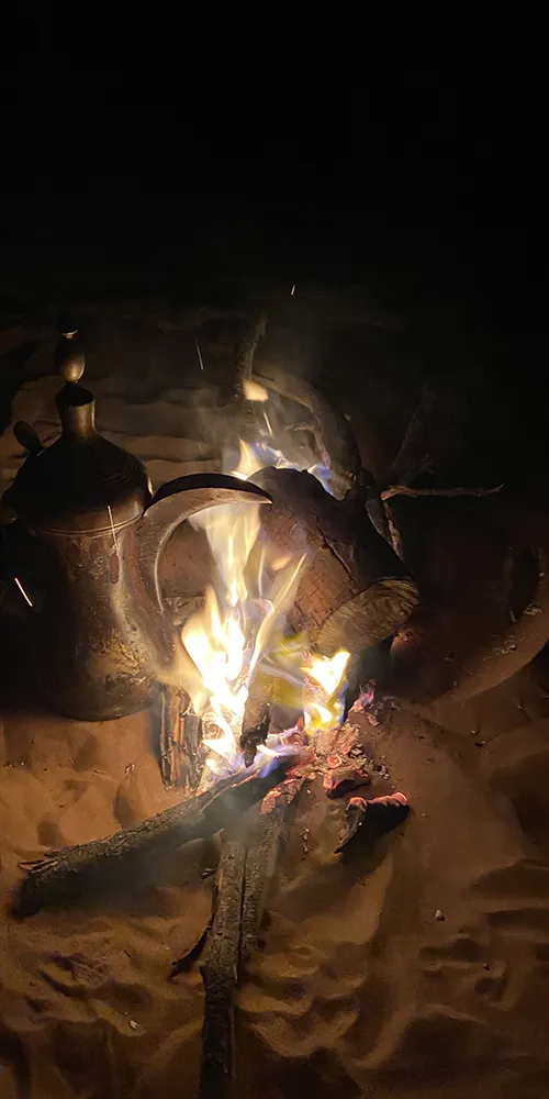 Feu de camp dans le désert — ambiance chaleureuse et conviviale sous un ciel étoilé.