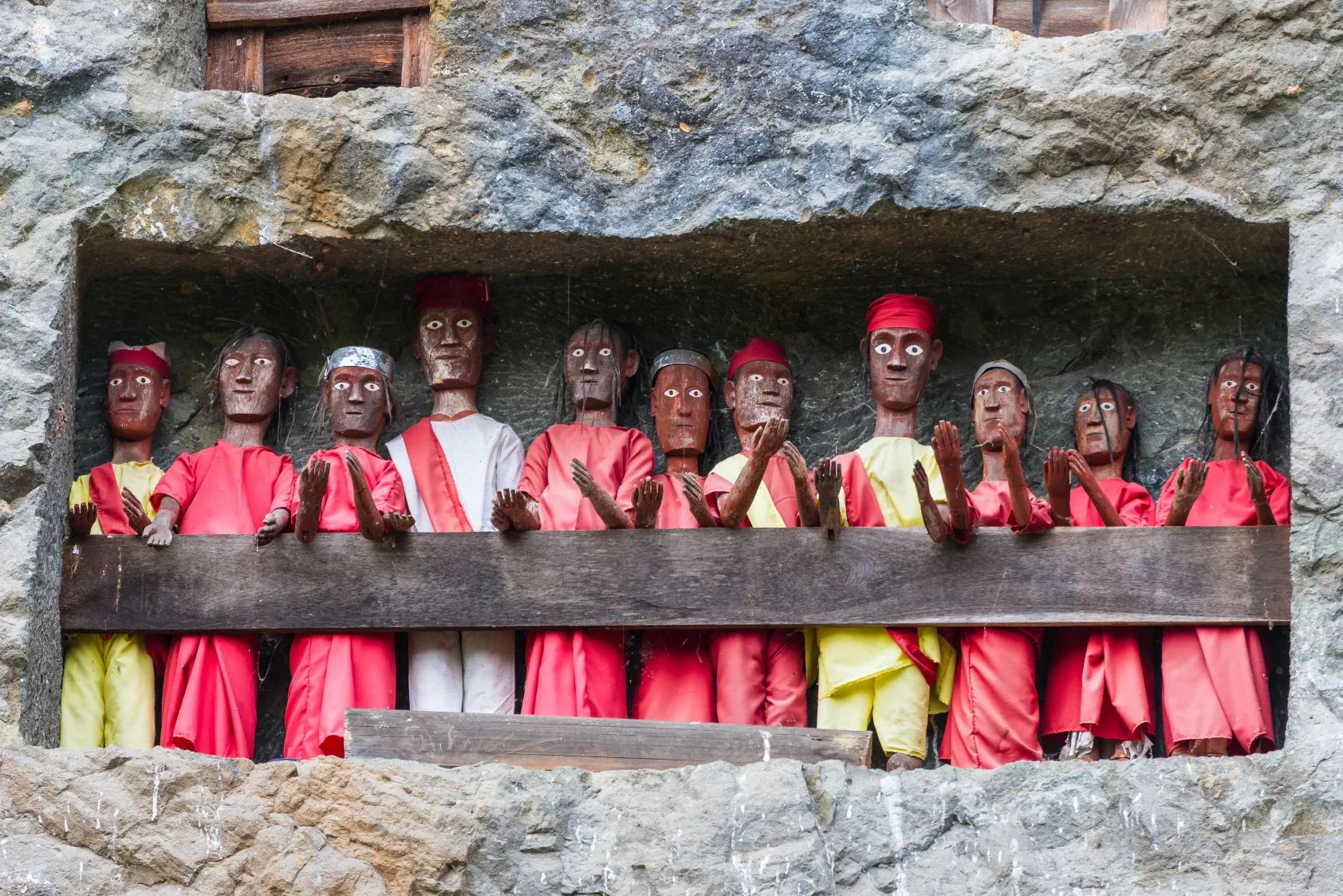Figures en bois colorées dans une alcôve rocheuse, offrant une vue fascinante et authentique.