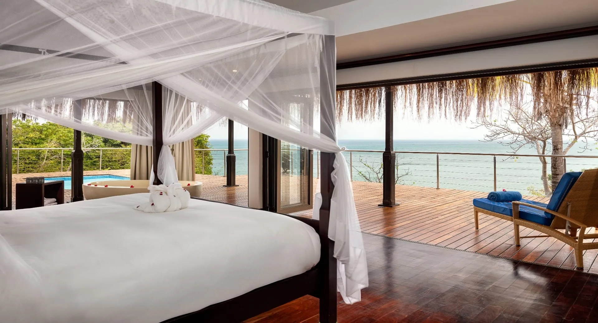 Chambre lumineuse avec vue sur l'océan, décorée de manière raffinée et entourée d'une nature luxuriante.