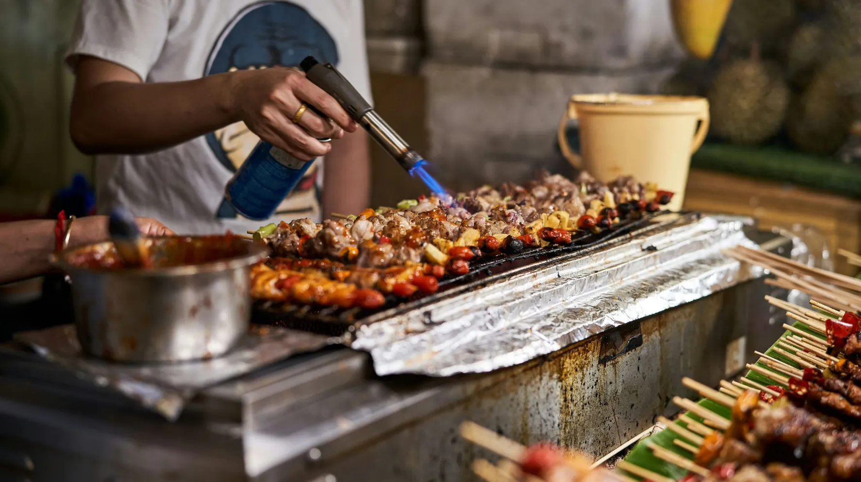 Street food coloré et savoureux, en pleine préparation sur un barbecue animé.