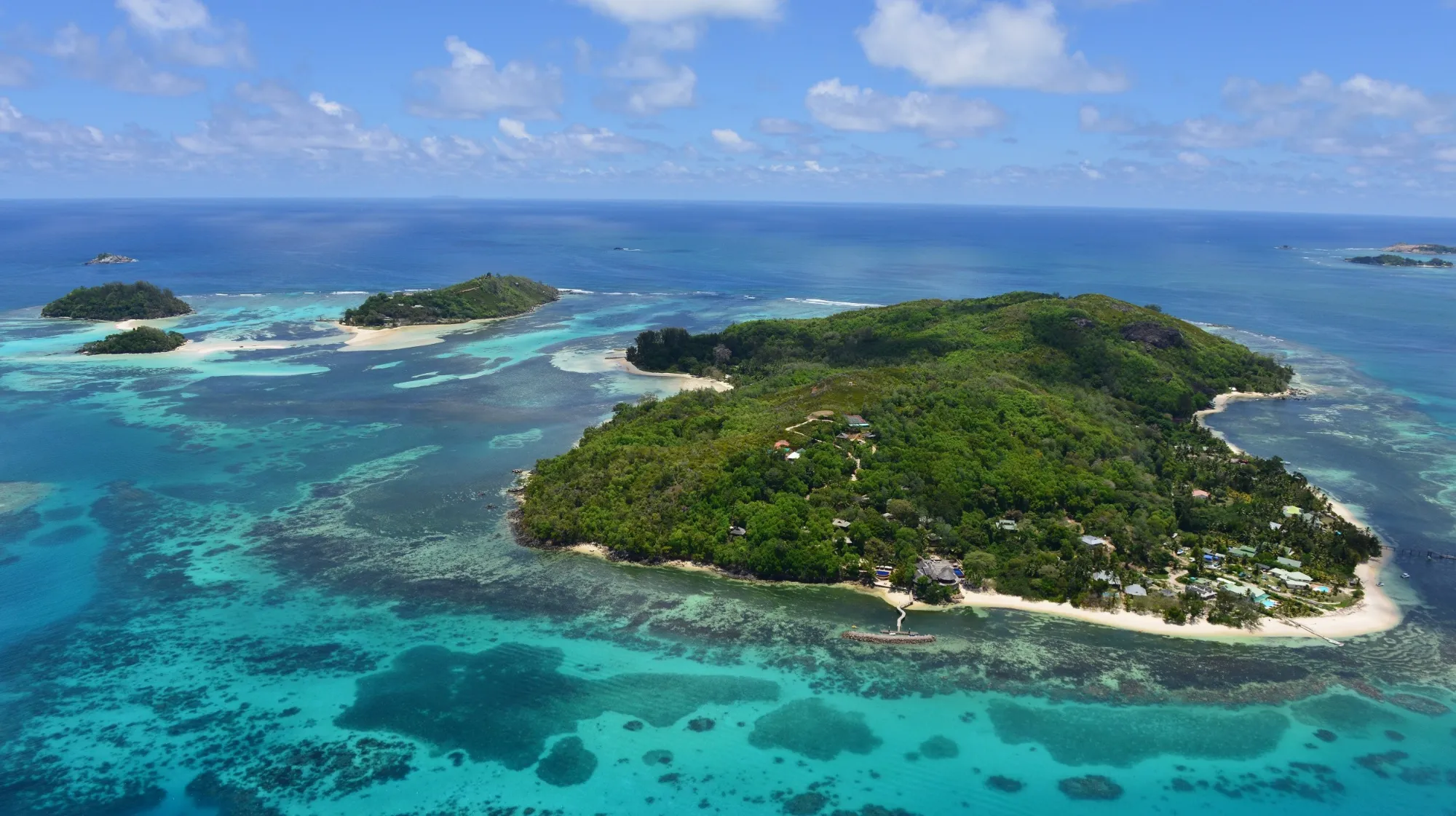 Île paradisiaque aux eaux turquoise, entourée de végétation luxuriante et de plages de sable fin.