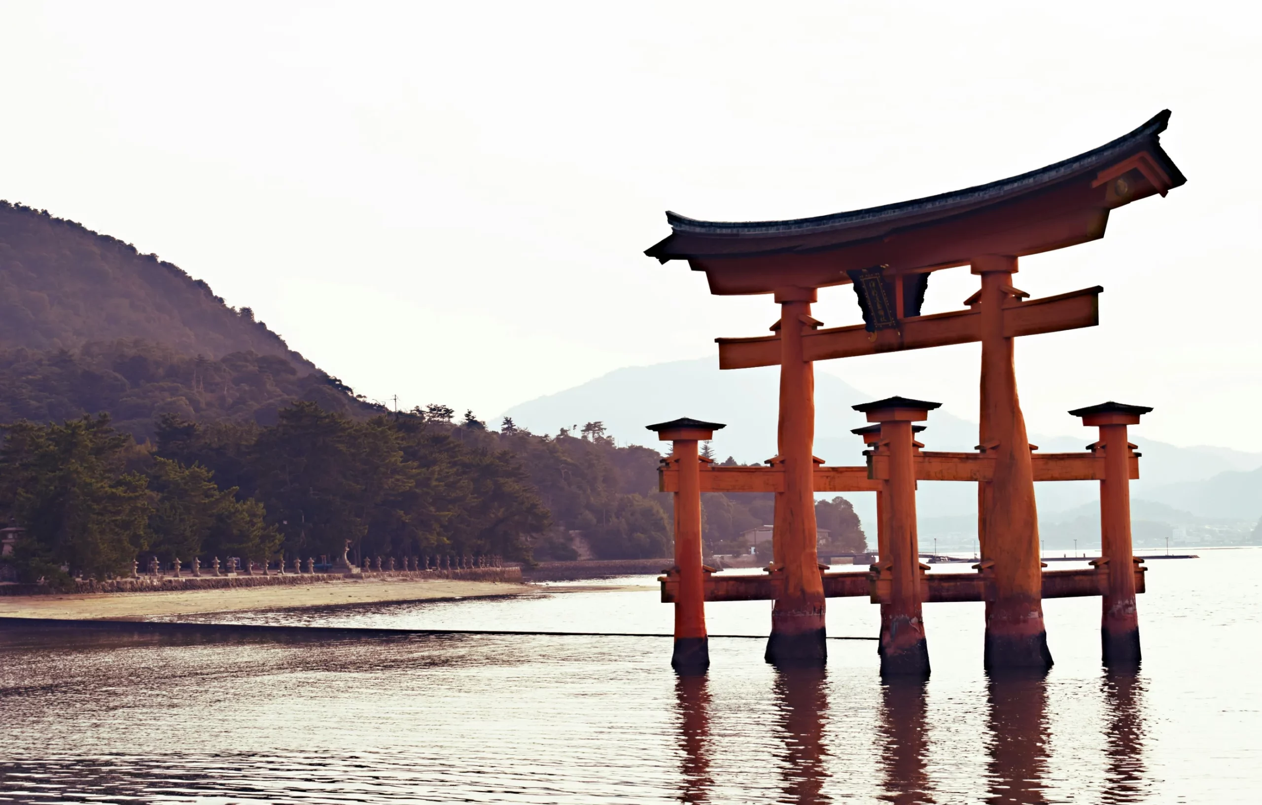 Torii, Japon — un symbole majestueux émergeant des eaux paisibles, entouré de montagnes verdoyantes.