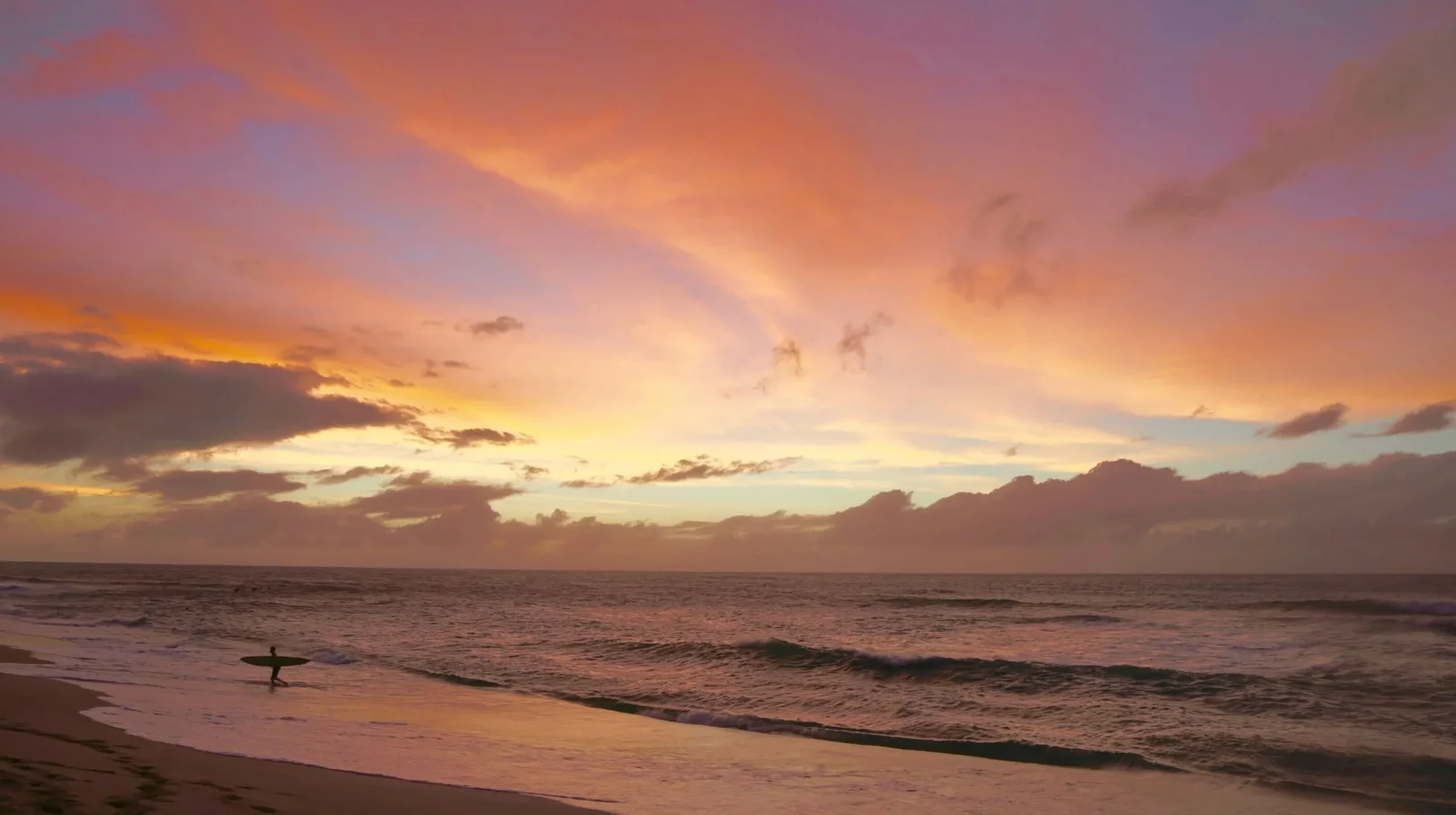 Coucher de soleil spectaculaire sur une plage paisible, reflet des couleurs chaudes sur l'eau.