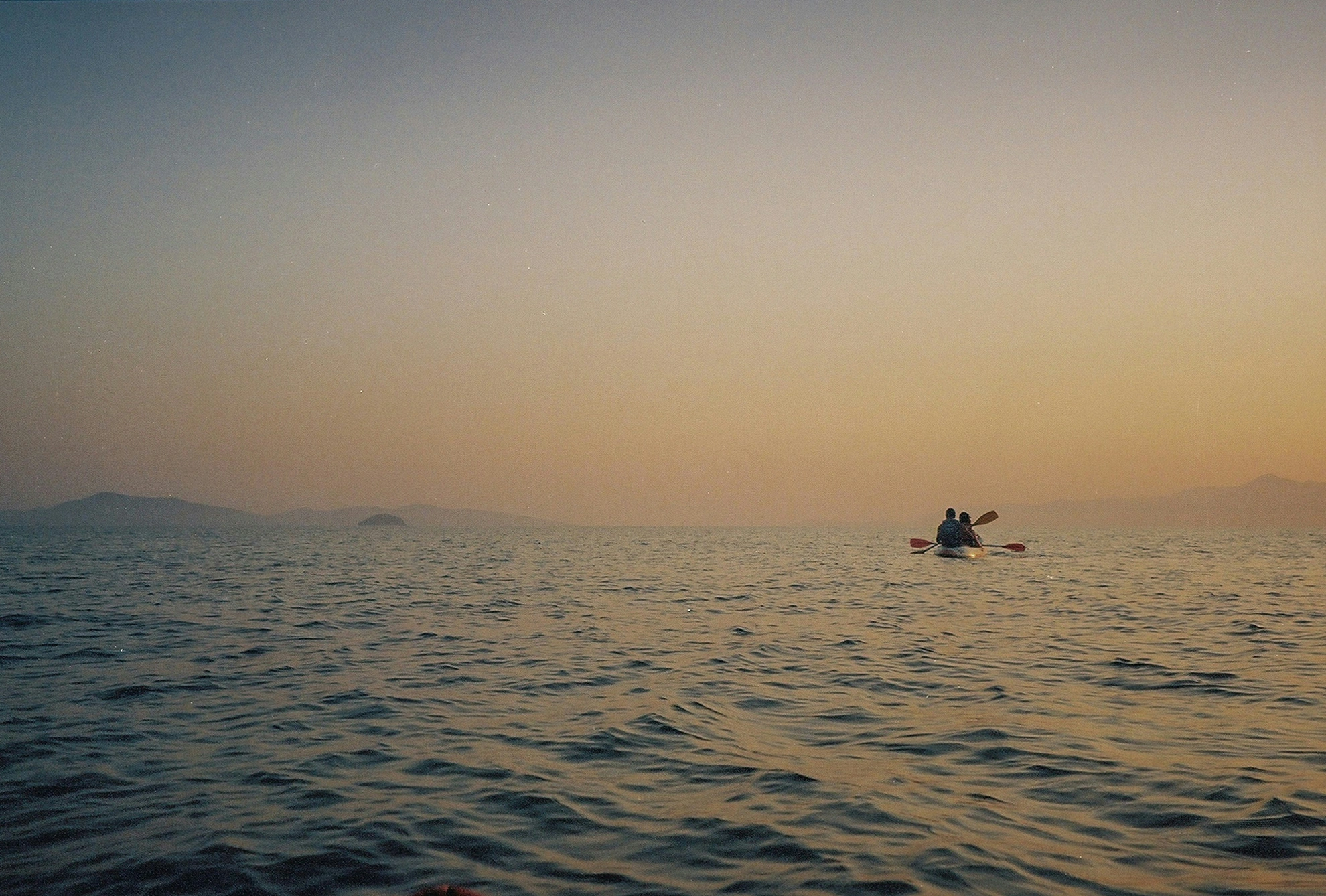 Canoë sur une mer tranquille au crépuscule, offrant une ambiance paisible et romantique.