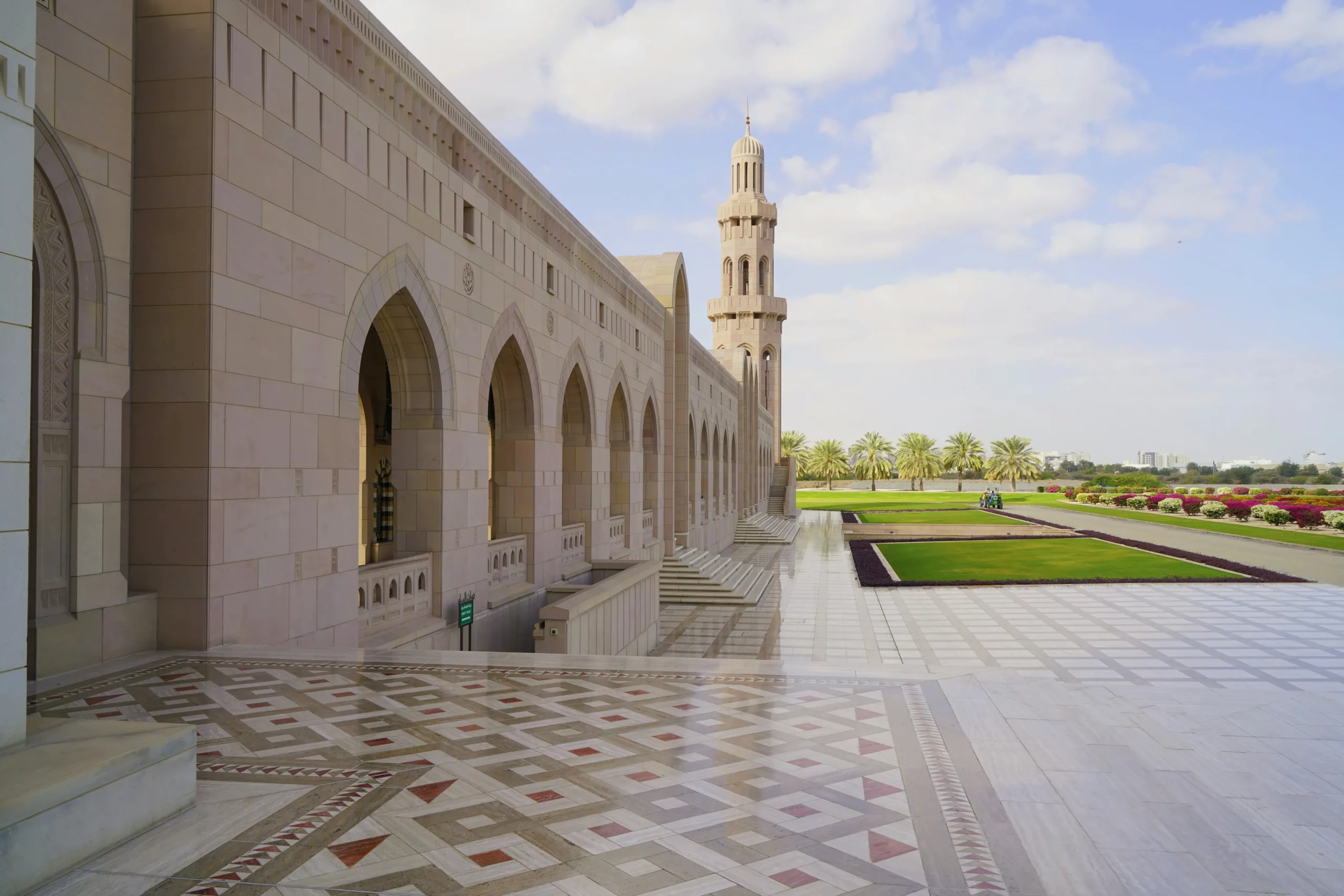 Oman — architecture majestueuse et jardins luxuriants sous un ciel lumineux.