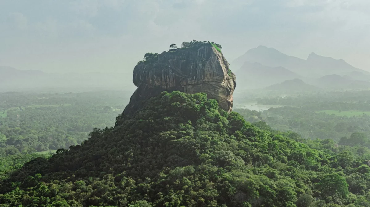 Rocher majestueux entouré de verdure luxuriante, offrant une vue spectaculaire sur le paysage environnant.