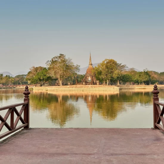 Un paysage paisible avec un temple au bord d'un lac entouré de verdure.