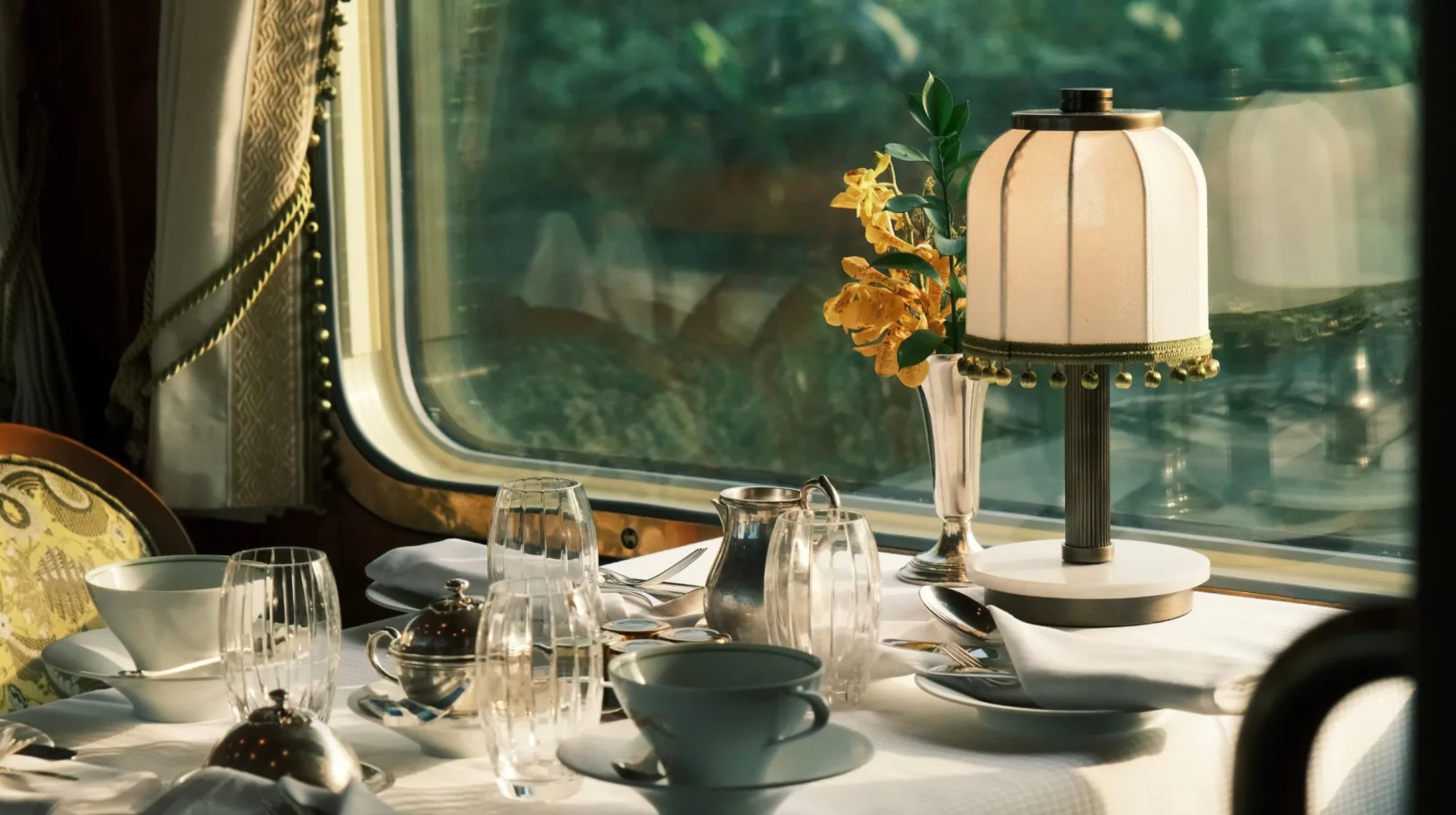 Table élégamment dressée avec une lampe et des fleurs, offrant une ambiance chaleureuse et conviviale dans un train de luxe le plus réputé au monde.