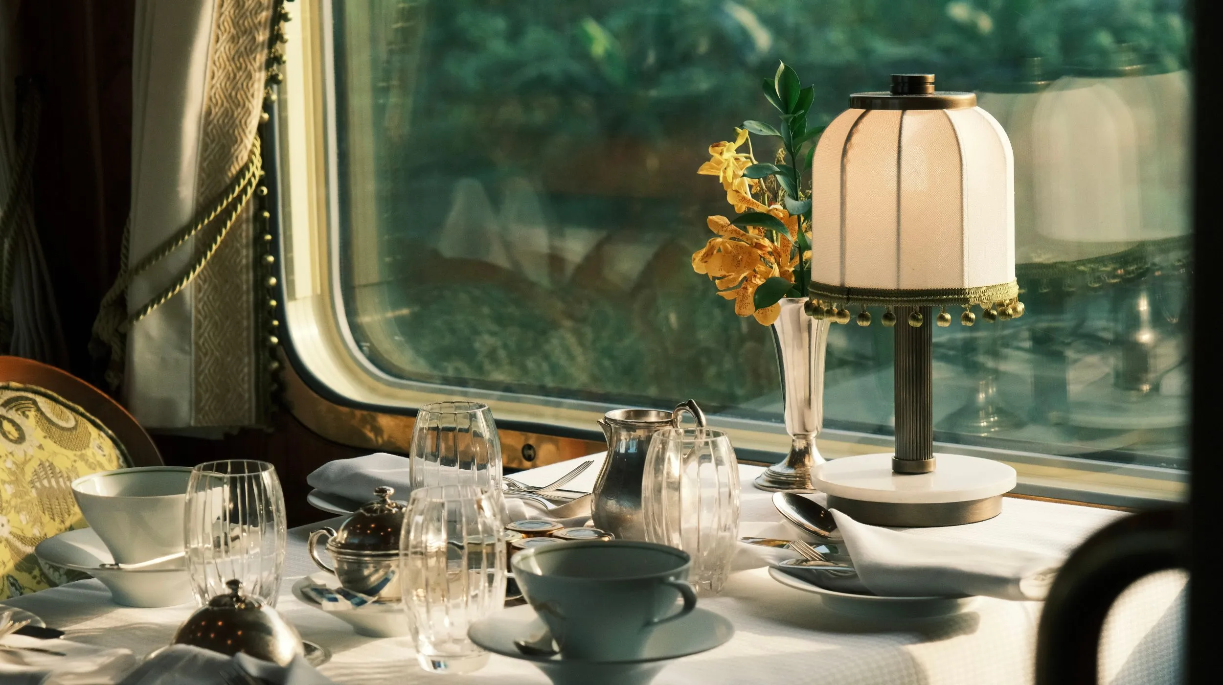 Table élégamment dressée avec une lampe et des fleurs, offrant une ambiance chaleureuse et conviviale.