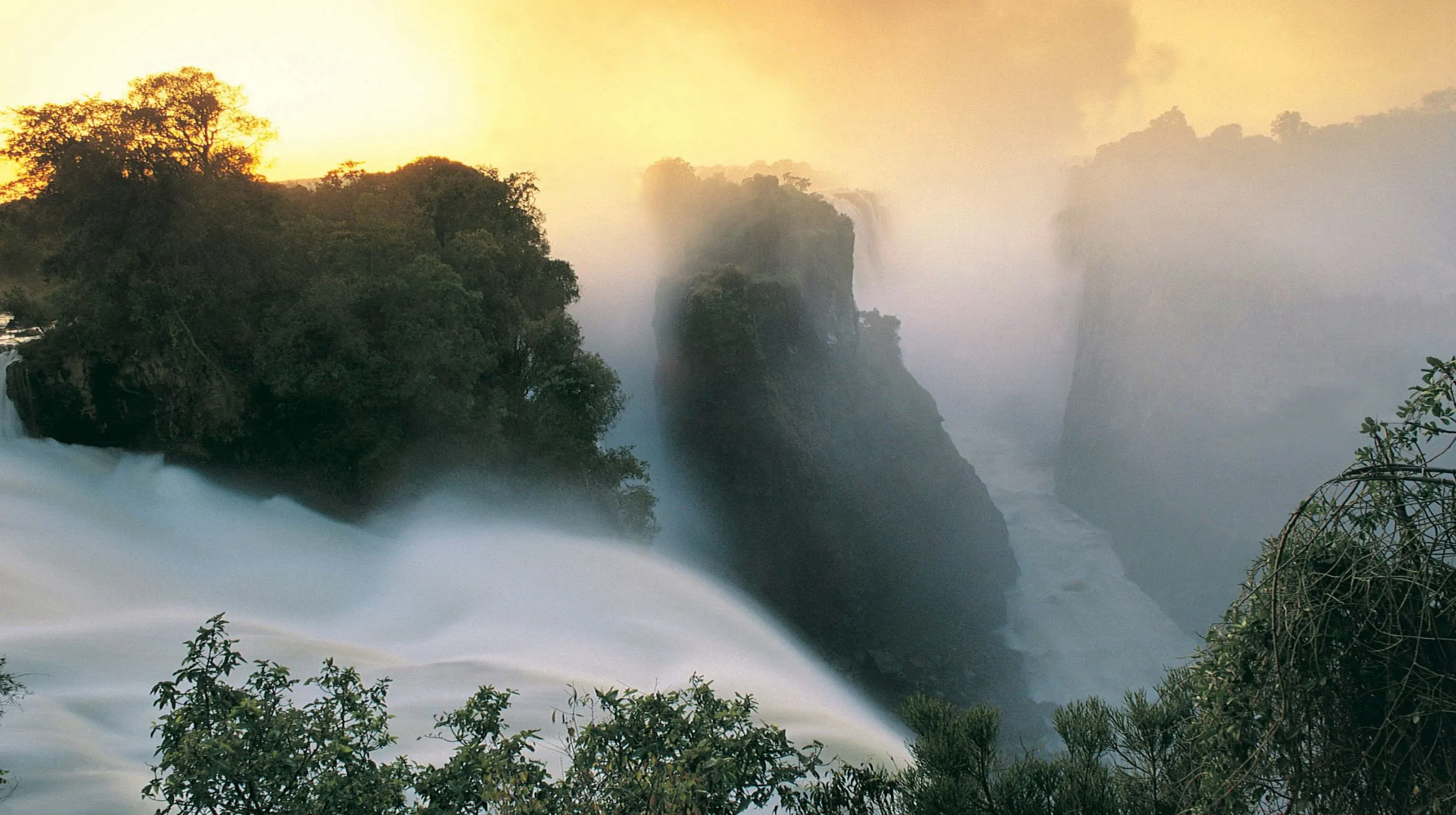 Chutes Victoria au Zimbabwe majestueuses entourées de brouillard et de végétation luxuriante, offrant un spectacle époustouflant.