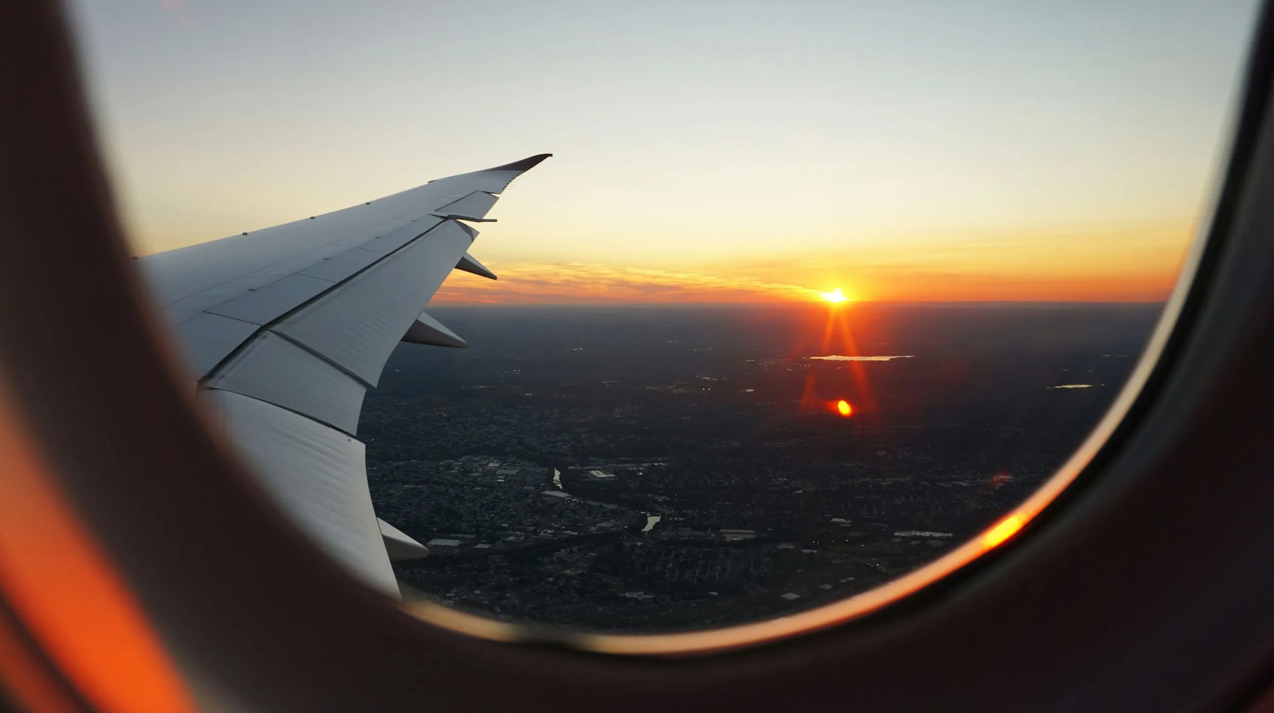 Vue spectaculaire d'un coucher de soleil depuis un avion, avec l'aile en premier plan.