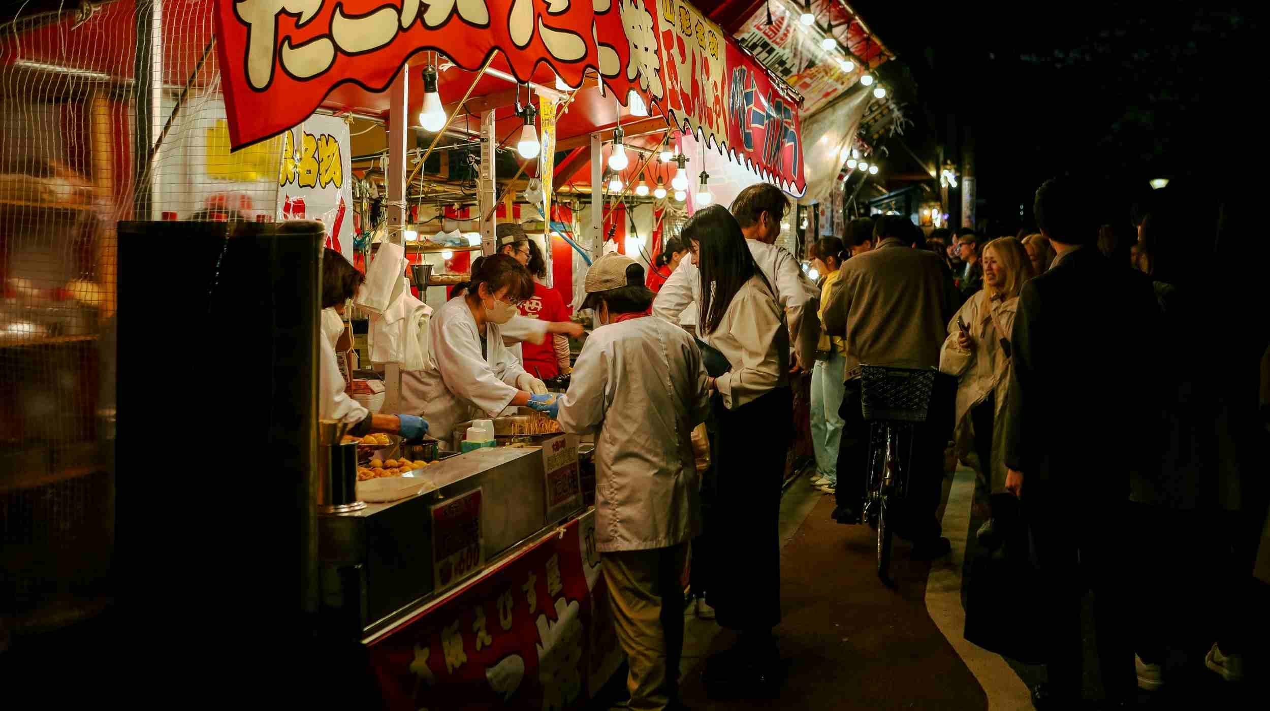 Marché de street food au Japon de nuit avec stands de nourriture et ambiance animée – expérience culinaire japonaise