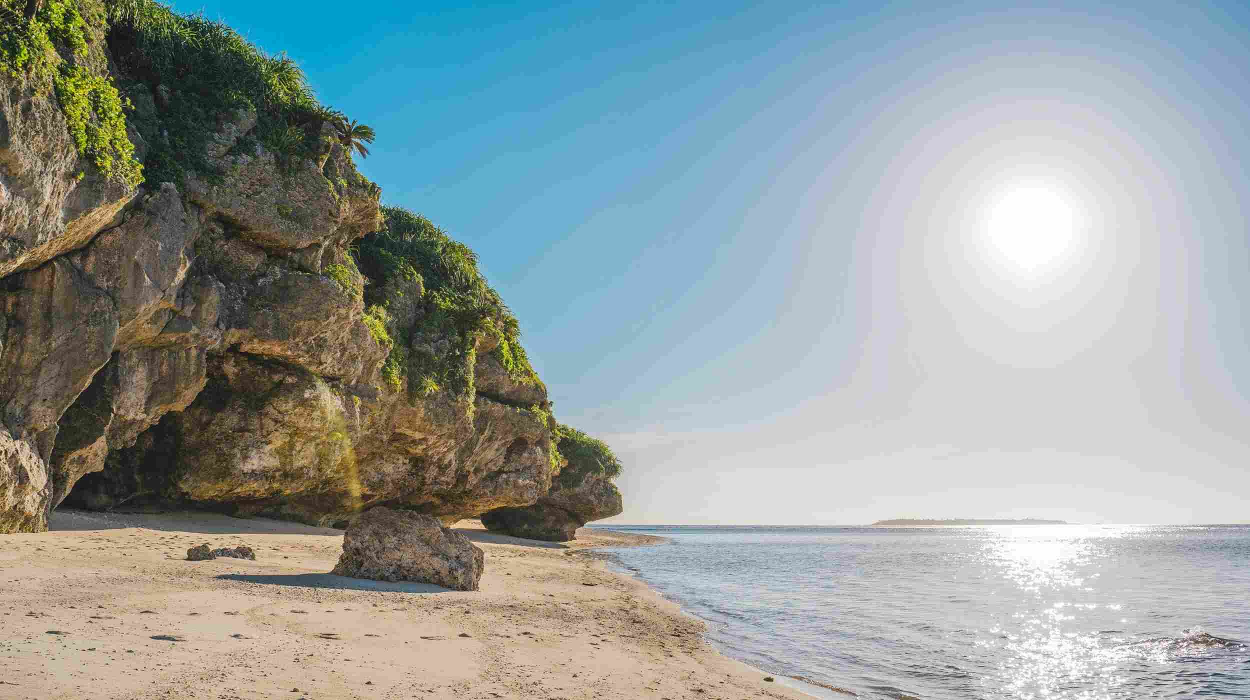 Plage sauvage d’Okinawa au Japon avec falaises rocheuses et mer calme sous le soleil – destination idéale pour un voyage au Japon en été
